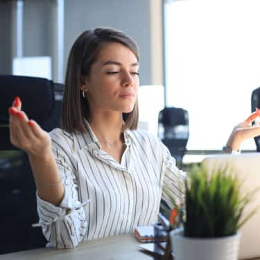 a woman meditates at her desk