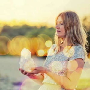 a woman holds and meditates on a crystal