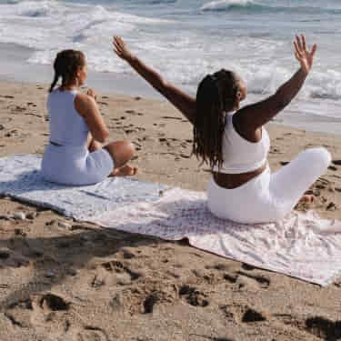 two women mediate on the beach