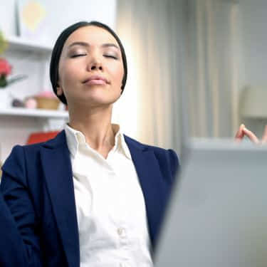 a person meditates in a busy workspace